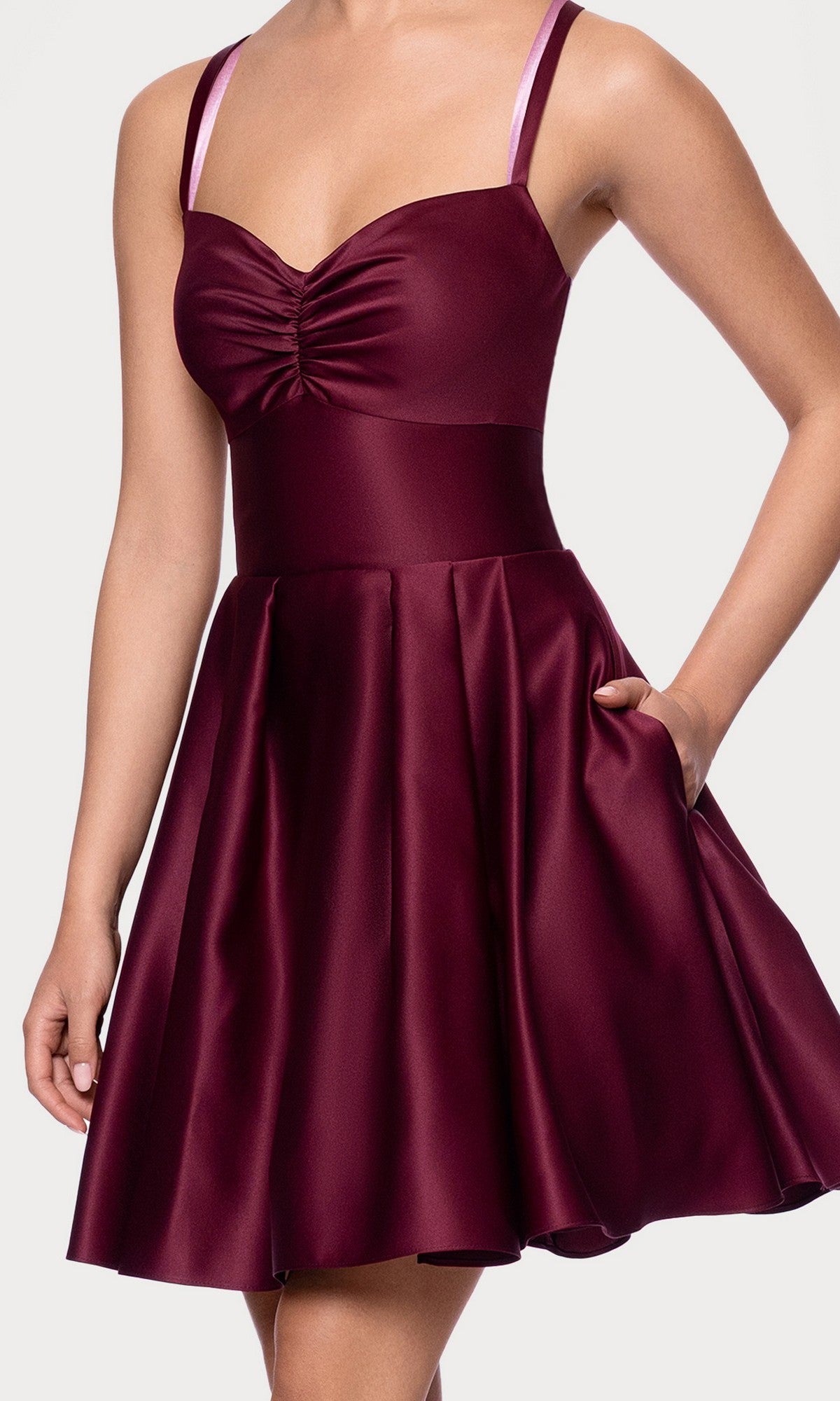A woman wears the Hunter Green Mini Hoco Dress (Blondie Nites 4927BN), a sleeveless satin A-line homecoming dress with a fitted ruched bodice, flared skirt, and one hand in her pocket.